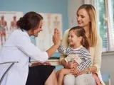 Pediatrician giving a young girl a high-five after her immunization visit