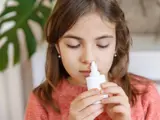 Girl using a nasal spray to relieve allergy symptoms