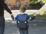 Child walking to school with parents, ready for back-to-school immunizations